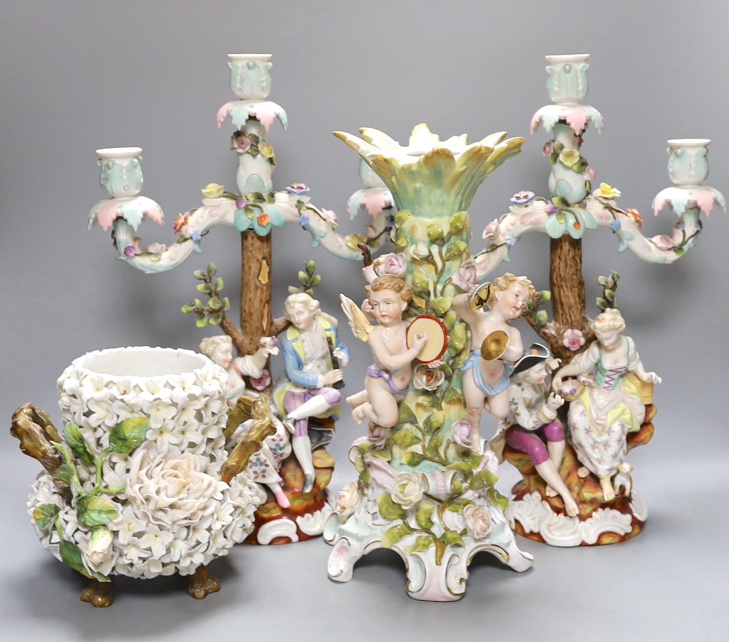 A pair of continental porcelain figural candlesticks and a similar candelabra base, together with a encrusted porcelain two handled jar with floral decoration, tallest 39cm, (4)